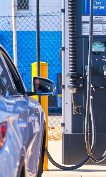 A man sits in his EV electric vehicle charging his car at a charging station