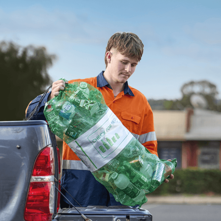 worker lifting a bag of containers from the back of a ute in a car park